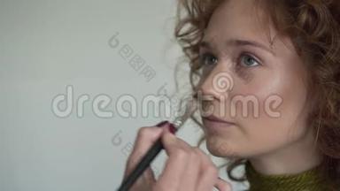 专业化妆师的特写镜头是将红色唇彩运用到模特身上。
